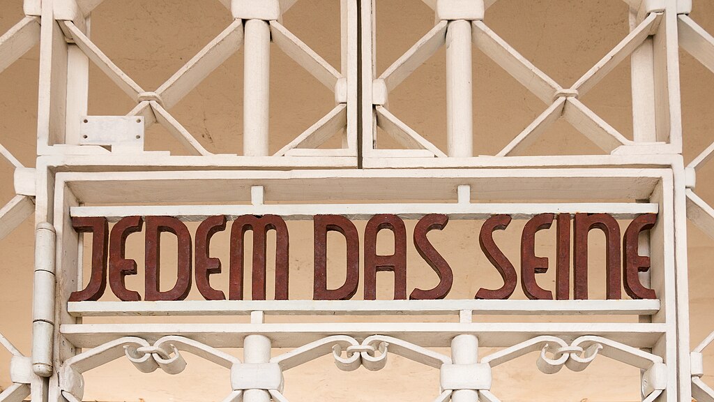 Zu sehen ist der obere Teil des Lagertors des KZ Buchenwald mit dem vom Bauhauskünstler Franz Ehrlich gestalteten Schriftzug 